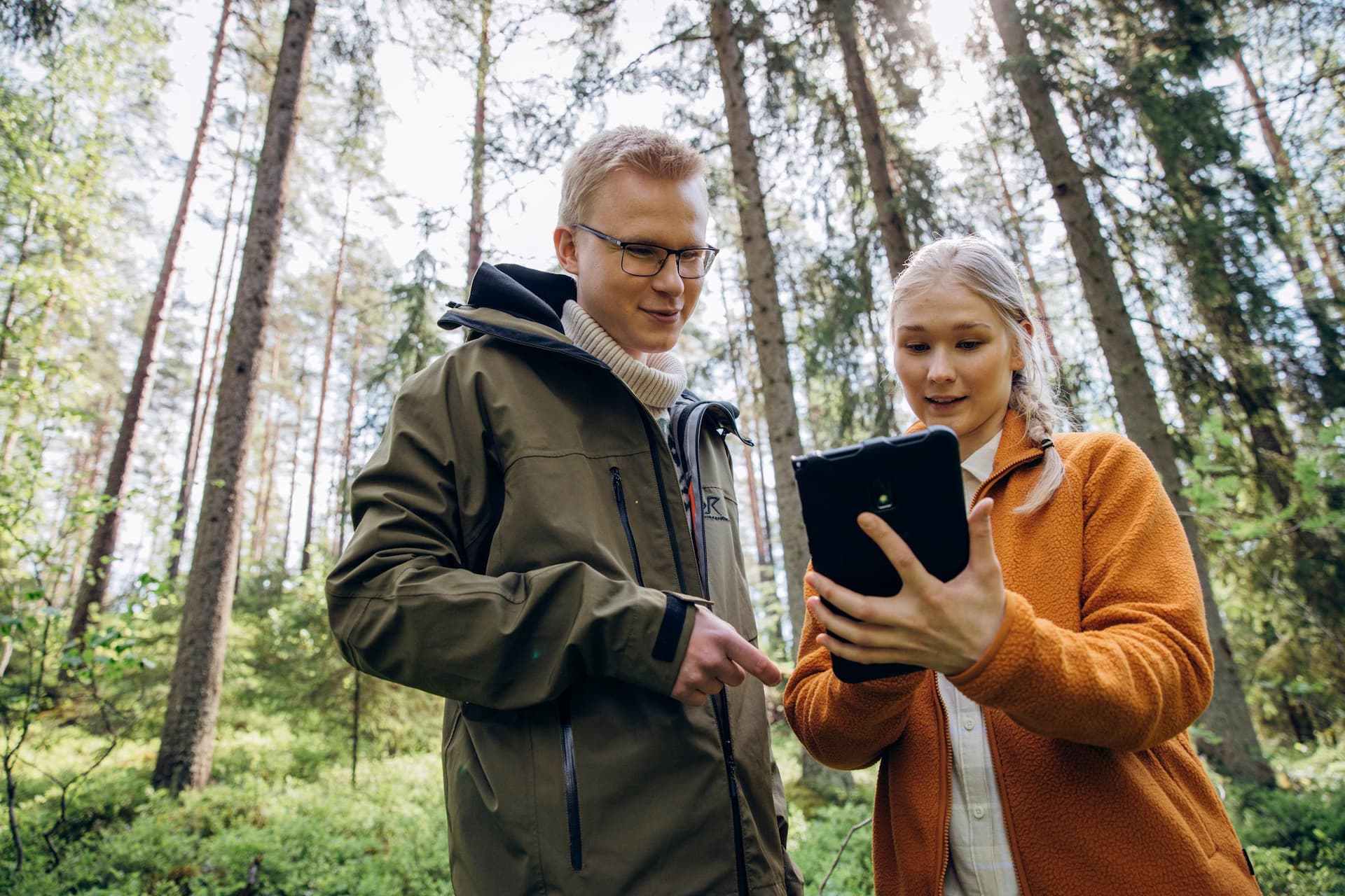 RFI brand photoshoot in Espoo, Finland. Two Environmental Specialists marking their location on a digital map in a forest, Nuuksio National Park.