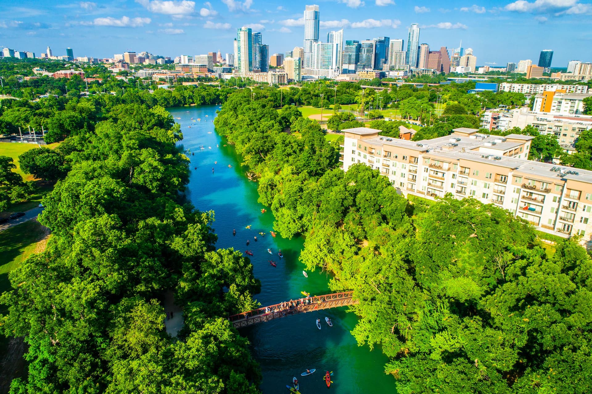 Austin Texas skyline cityscape aerial drone view above green landscape Barton creek flowing into town lake