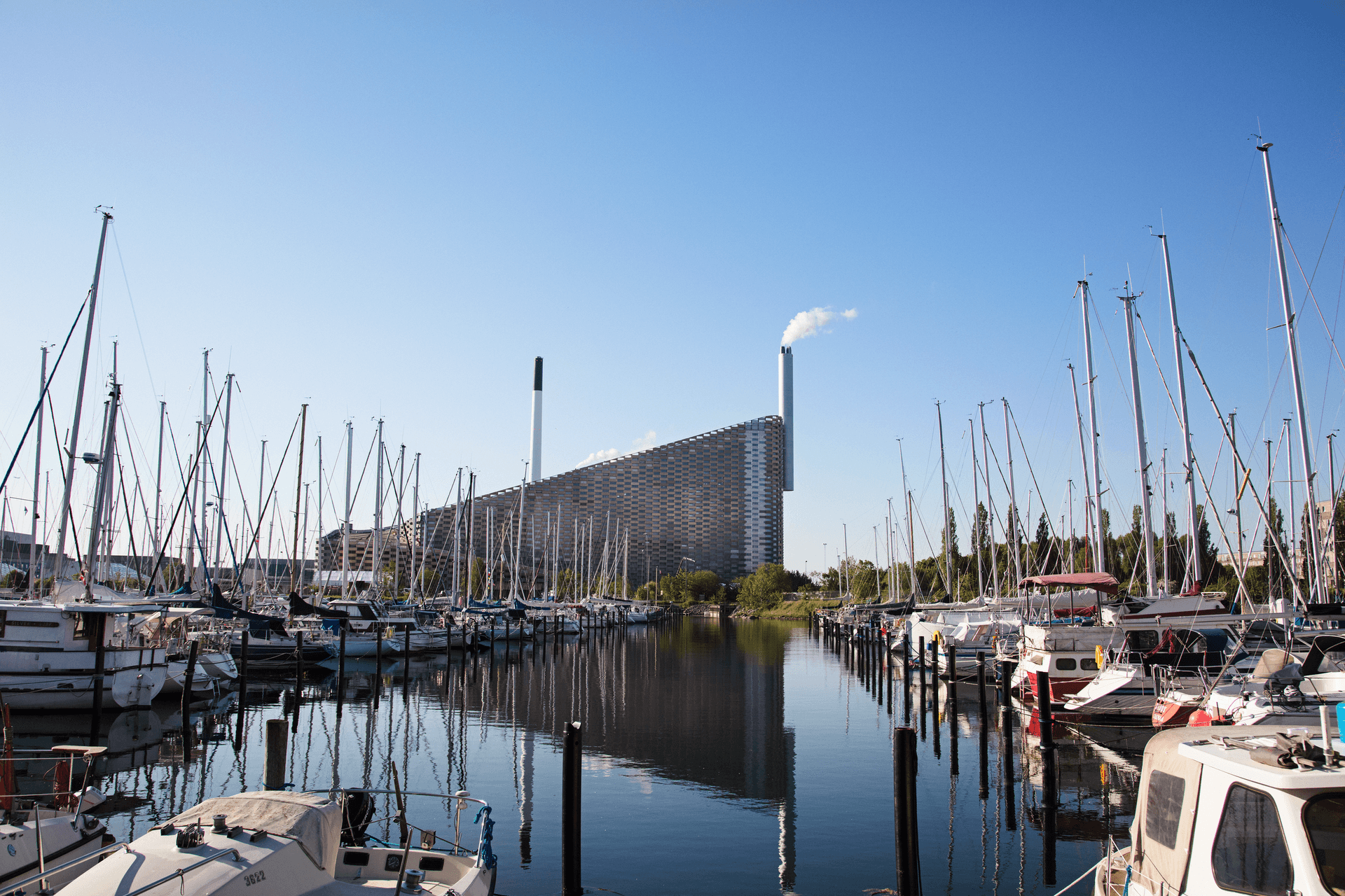 view of Amager Bakke waste-to-energy plant with harbour and boats in the foreground