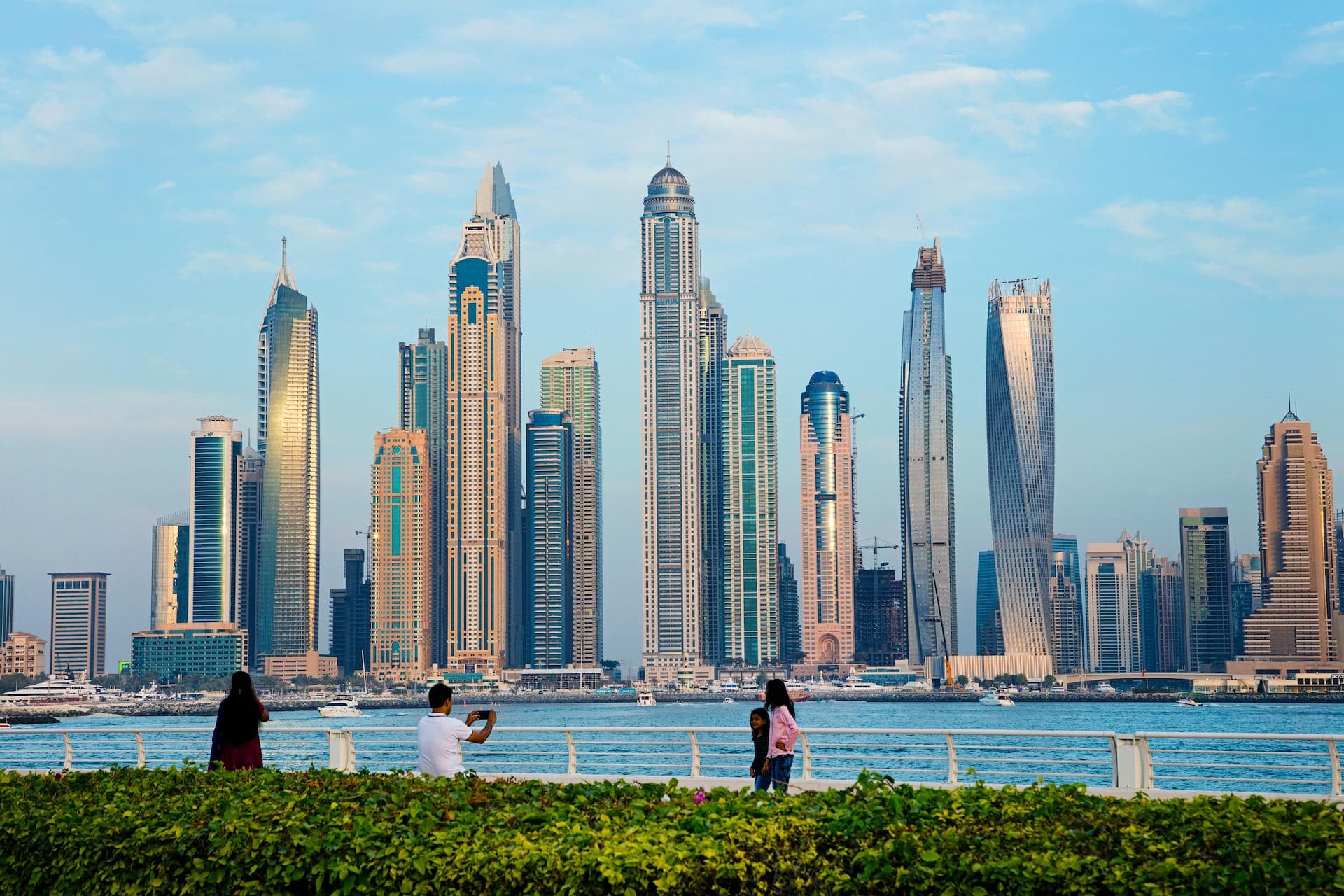 People walking on the harbour front in front of Duabi high-rise skyline