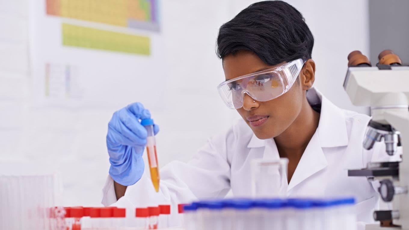 A beautiful young scientist dropping a substance into test tubes in her lab