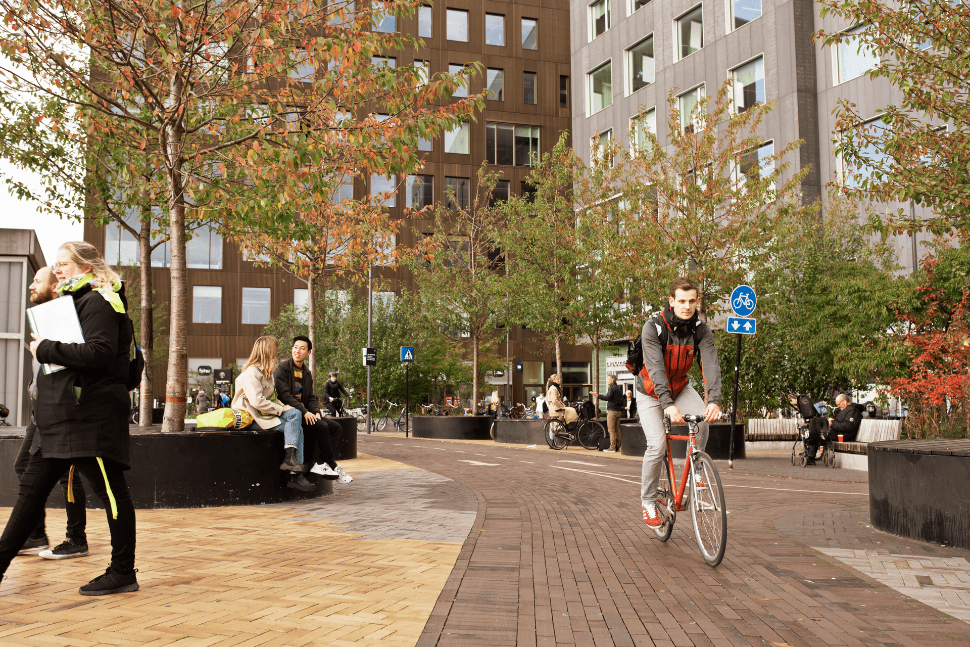 two people talking at  square at Bohrs Tower and Carslberg Station, bike passing by